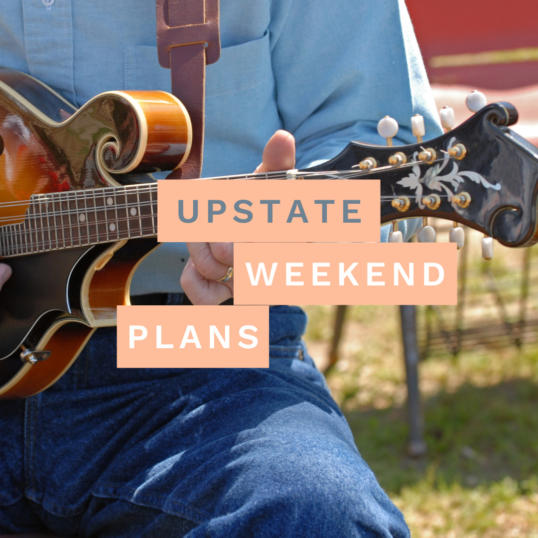 close-up of a man playing a ukulele on his knee with text written across the photo "Upstate Weekend Plans"