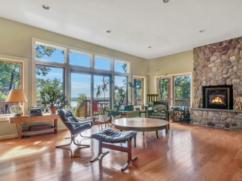 Living room and fireplace with table and chairs and a full wall of windows at 71 Carly Road in Woodstock, NY listed by Halter Associates Realty.