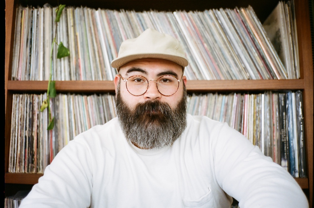 DJ Andre Acosta  in front of a wall of vinyl