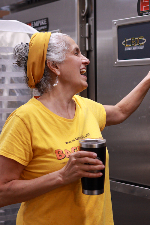 Beth George holding a coffee cup and looking at her bagel oven at Bagel-ish in Beacon, NY.