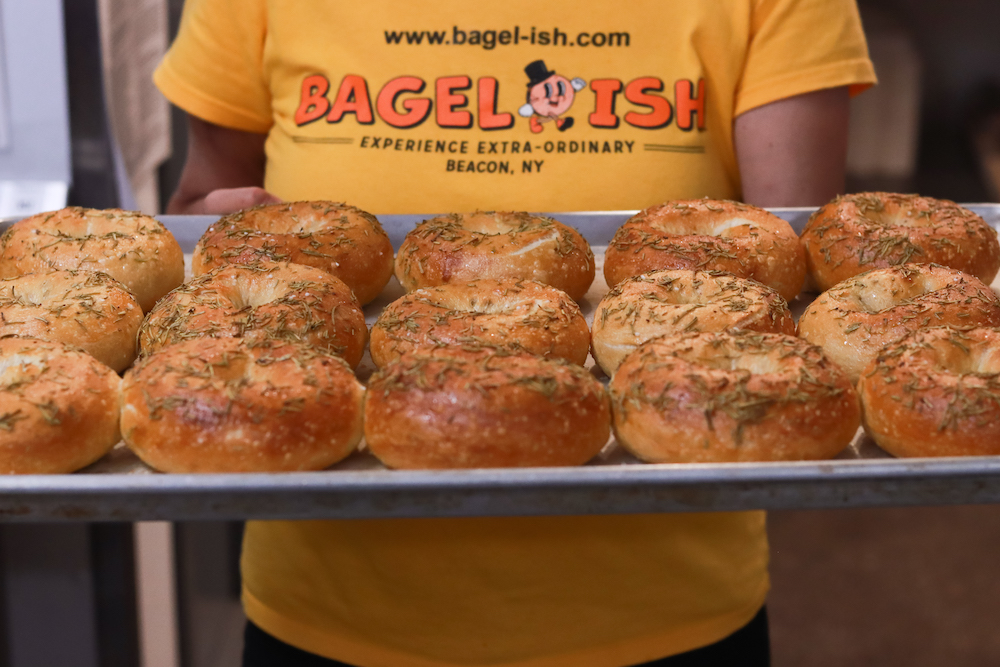 Beth George holding a tray of Rosemary bagels at Bagels in Beacon, NY.