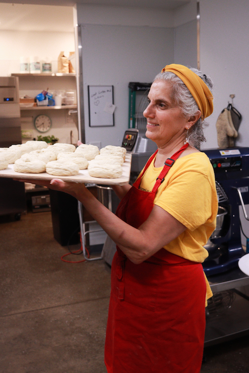 Beth George carrying a tray of raw bagels at Bagel-ish in Beacon, NY.