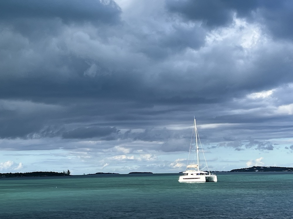 Sailboat in the distance under dark clouds. 