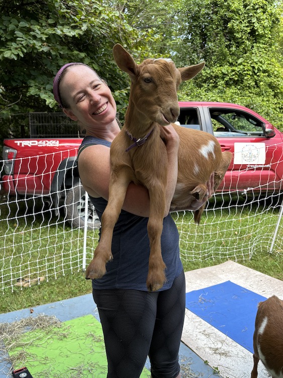 Happy yogi and baby goat at Woodstock Goat Yoga in Shady, NY.