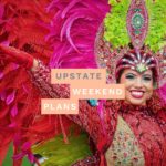 Woman in Caribbean V=Carnival costume with the "Upstate Weekend Plans" text written across the Hudson Valley, NY photo.