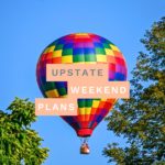 Hot air balloon in the sky with the "Upstate Weekend Plans" text written across the Hudson Valley, NY photo.