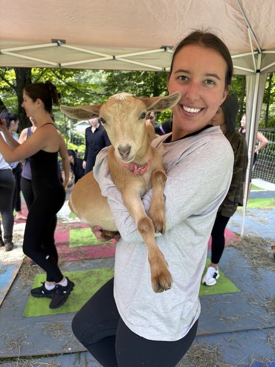 Happy Yogi with baby goat at Woodstock Goat Yoga in Shady, NY.