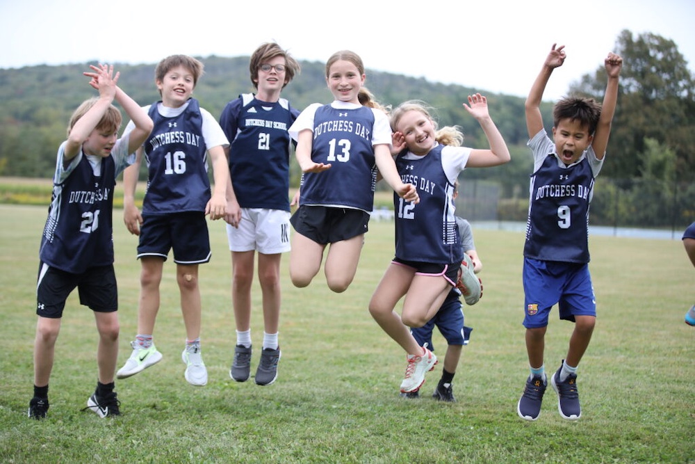 kids in sports uniforms jumping on the field at Dutchess Day School in Millbrook, NY