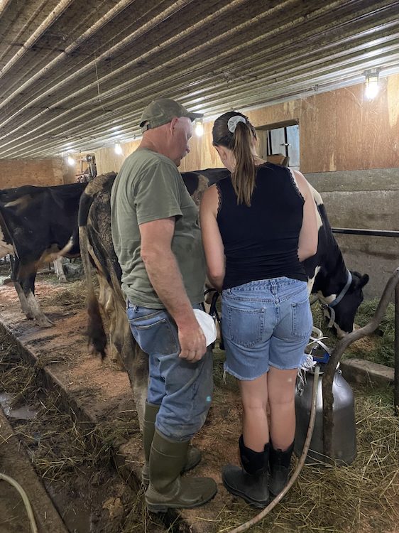intern Kristen being mentored by farmer Barton about milking cows at the Hilltop Farm in Accord NY