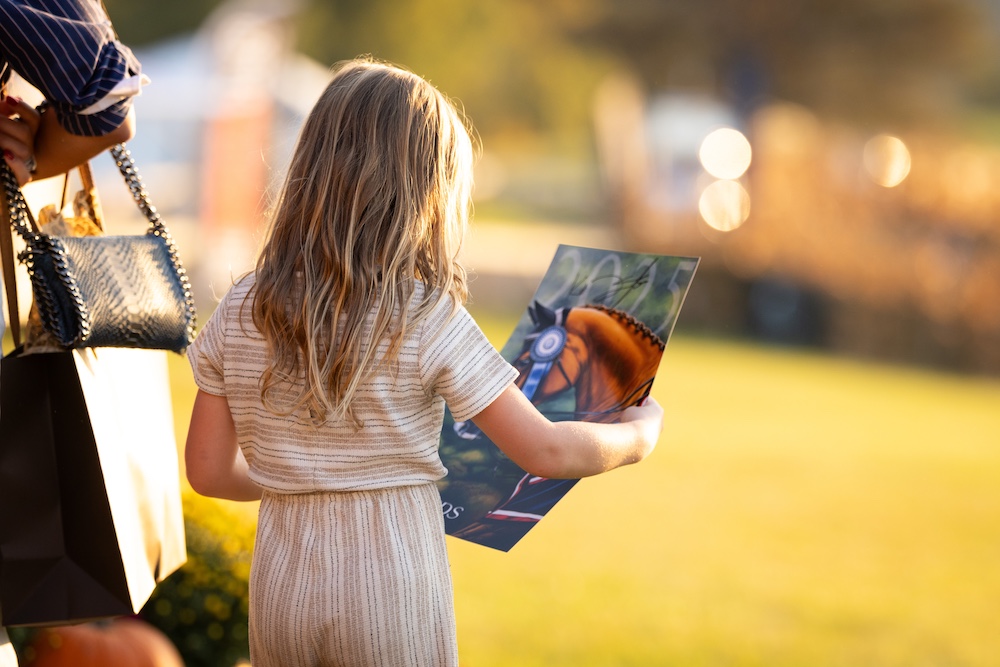 young girl looking at a horse show poster at Silo Ridge Masters CSI3 Grand Prix at The Highlands Stud Farm in Amenia NY