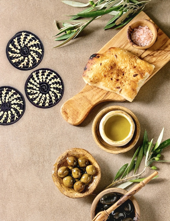 Reflektion Design Pine Needle Coasters from Aphrochic, olives, bread on cutting board.