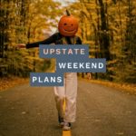 woman walking with pumpkin on her head down a country road with the "Upstate Weekend Plans" text written across the Hudson Valley, NY photo.