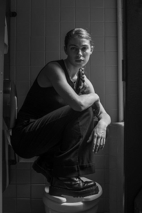 by Photographer Brooklyn Zeh in 2015 crouched on a toilet seat in the bathroom