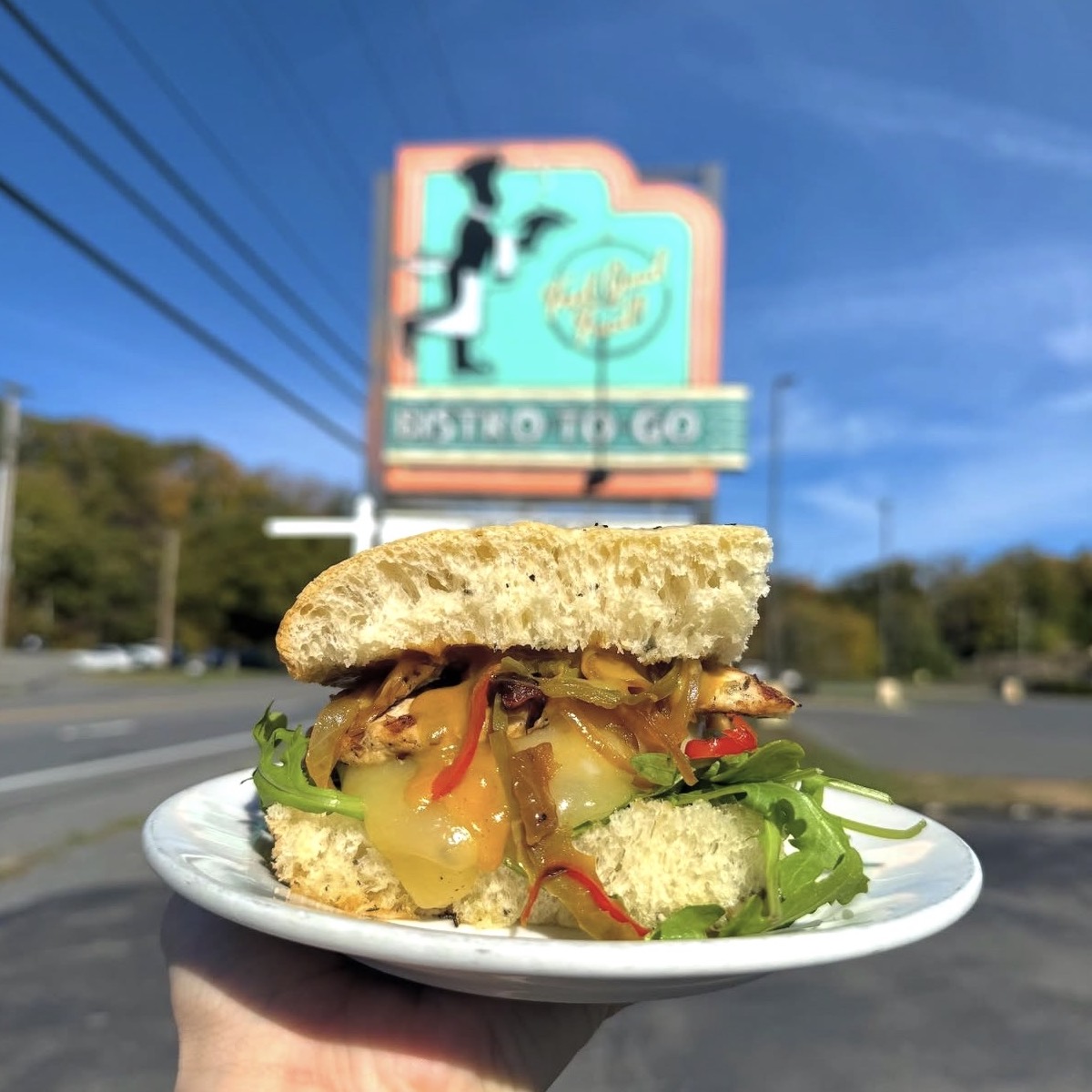 Blue Mountain Bistro to Go sandwich on foccacia with sign in backgroud on Rt. 28 in Kingston, NY.
