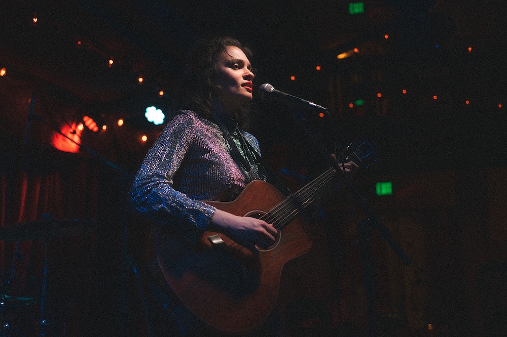 Ginger Winn singing and playing guitar on stage by Photographer Brooklyn Zeh