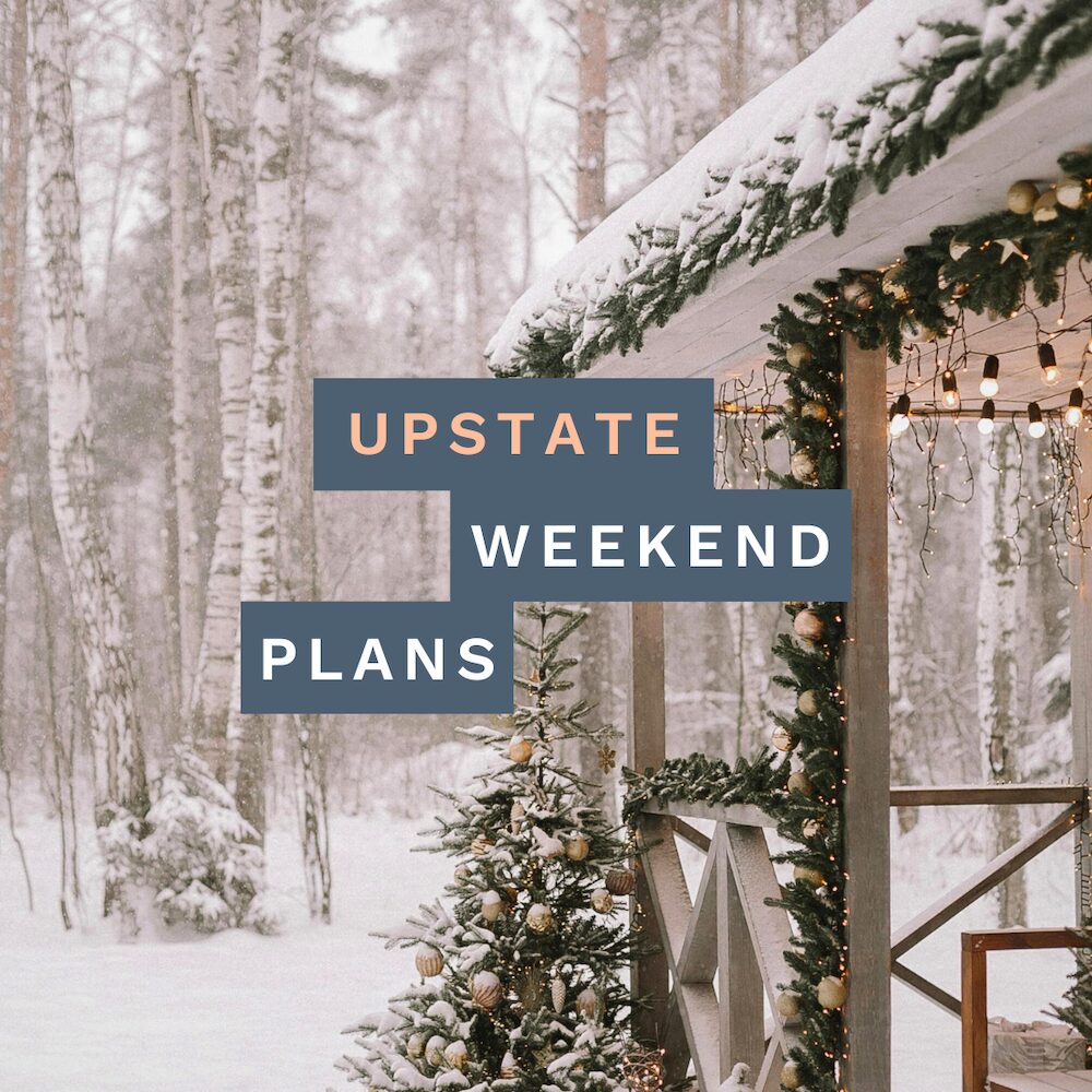 snowy cabin in the woods with holiday decorations with the "Upstate Weekend Plans" text written across the Hudson Valley, NY photo.