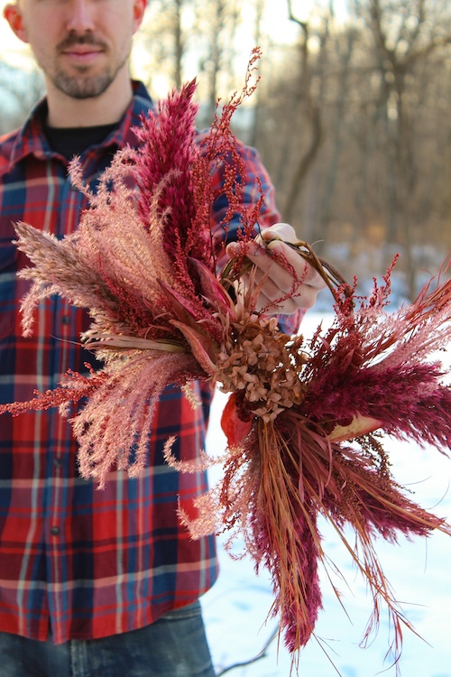 Carter Harrington holding his dried flowers arrangement outside at Hort & Pott in Freehold NY