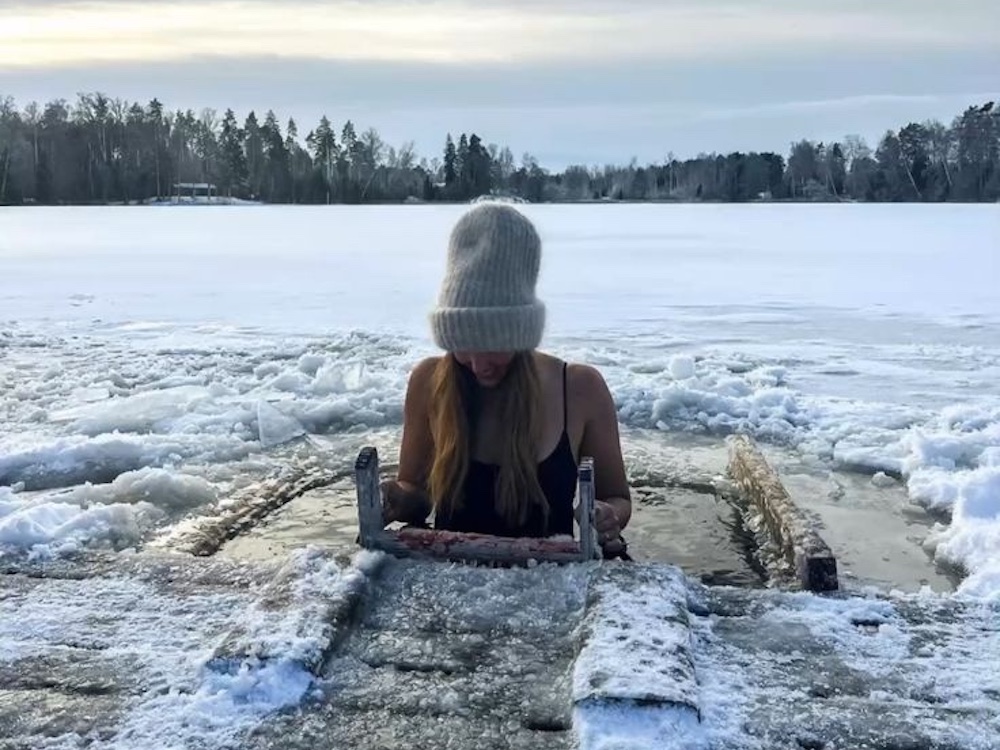 a woman dipping into the ice cold water in winter