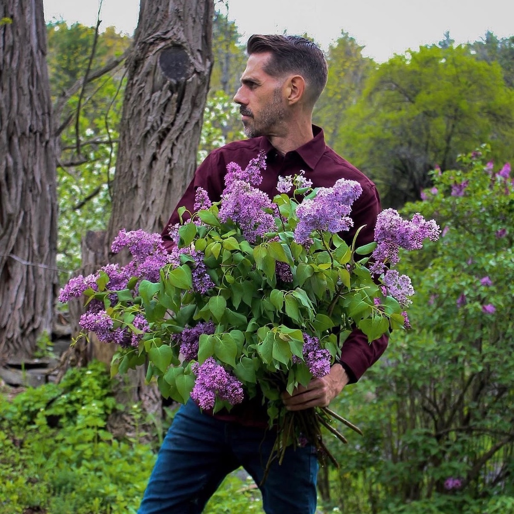 Todd Carr holding lilacs outside in Spring at Hort & Pott in Freehold NY