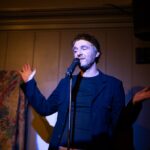 Paul Willis on a stage doing stand-up comedy