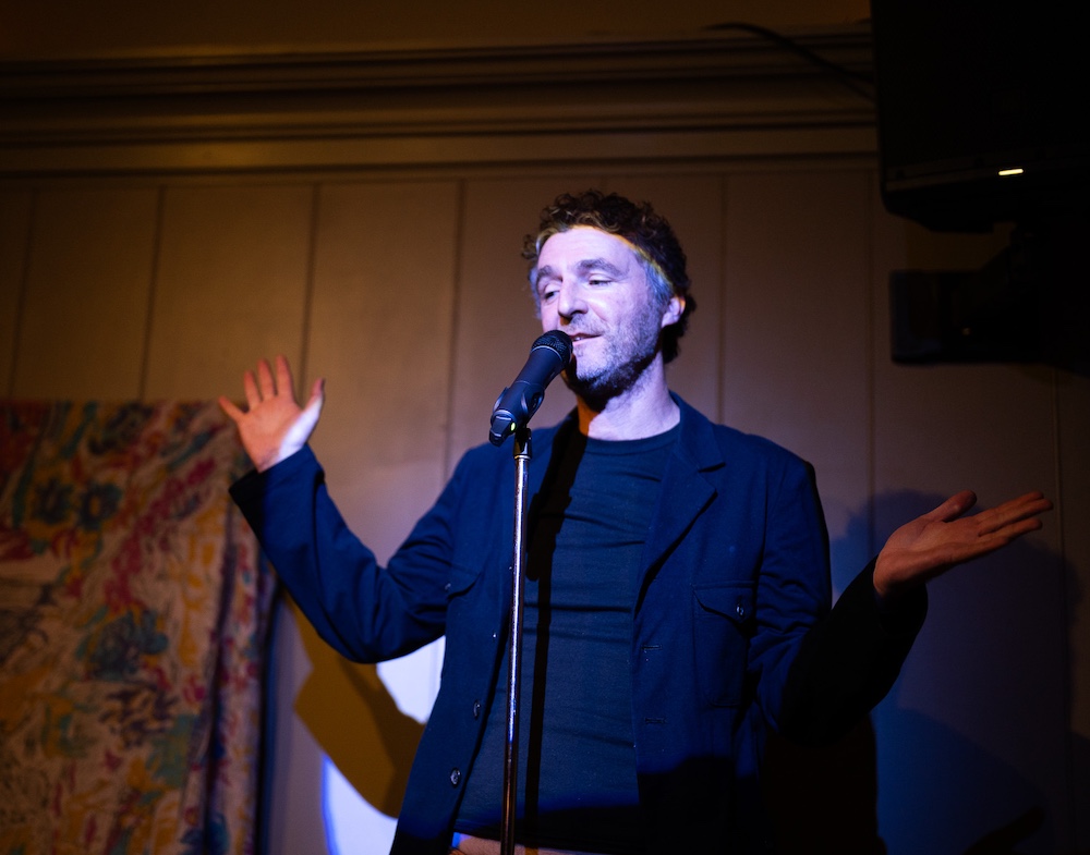 Paul Willis on a stage doing stand-up comedy