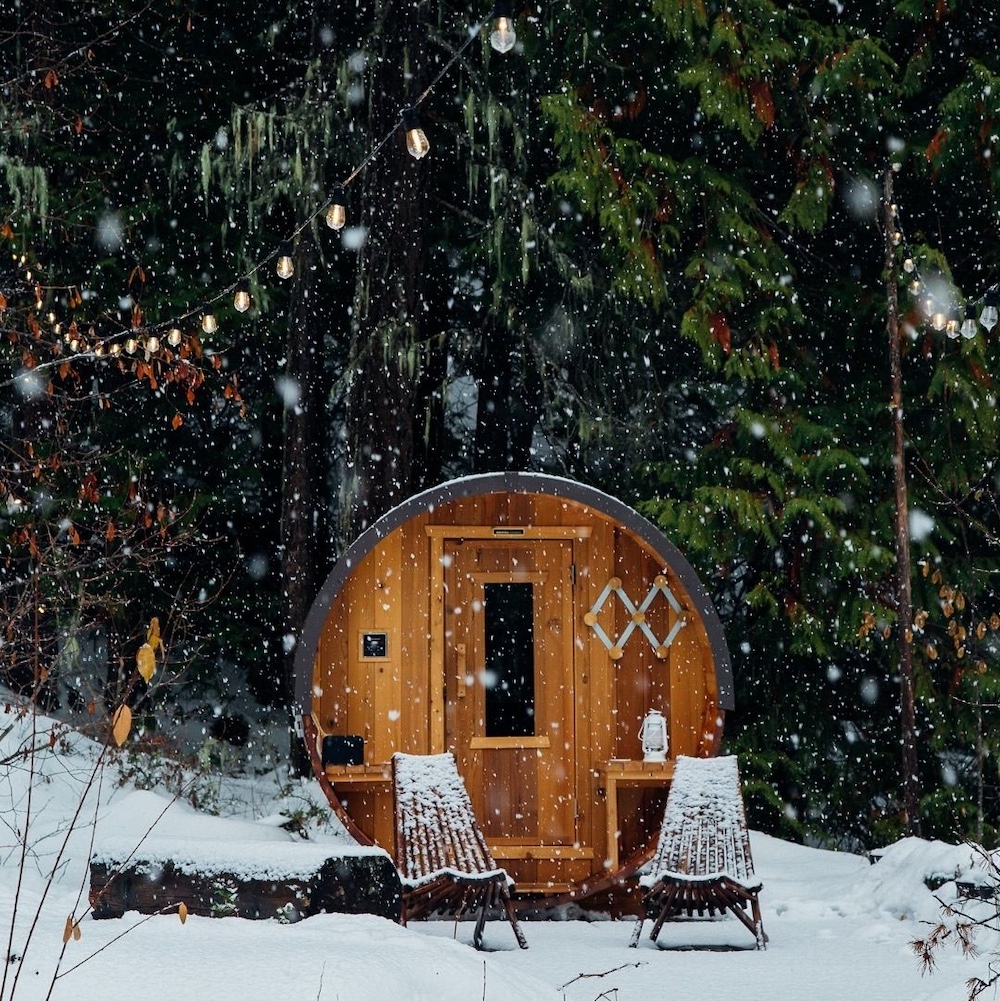 exterior of a sauna with snow falling and two chairs