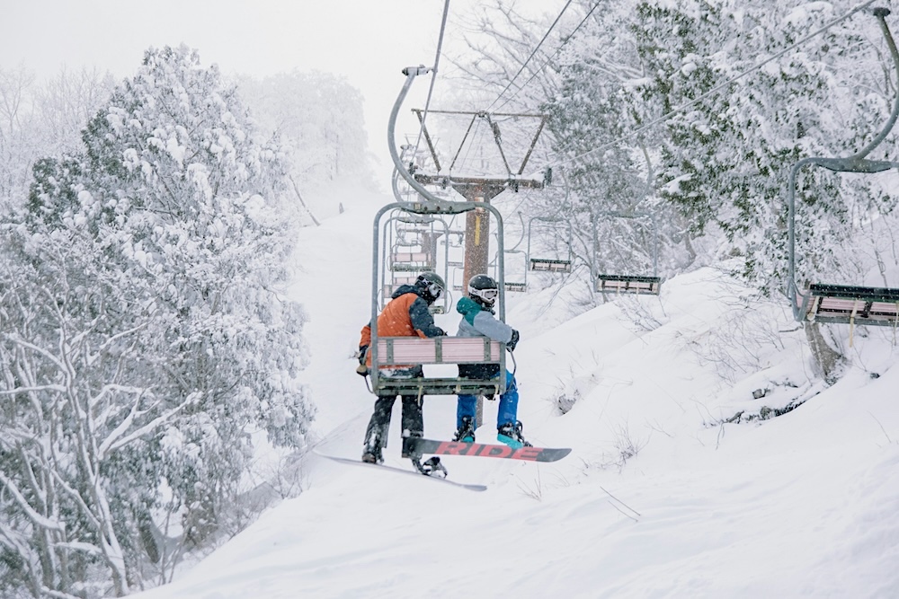 two people on a ski lift while snowing