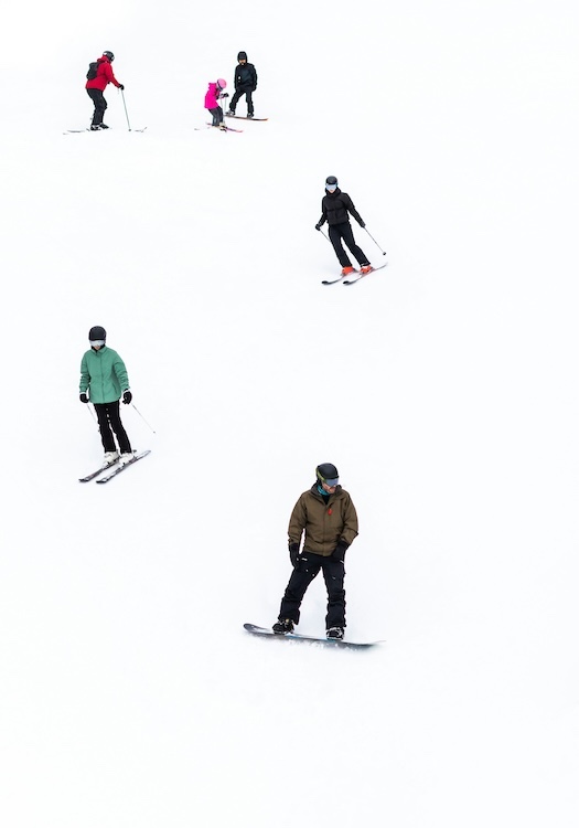 people skiing and snowboarding down a ski slope