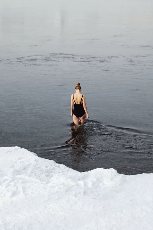 a woman wading into the cold water in winter