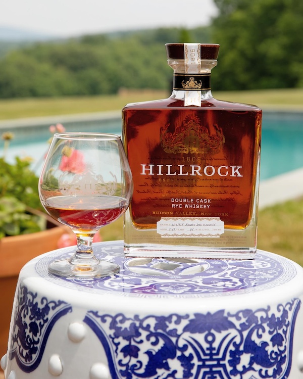 bourbon bottle and glass by the pool by Hillrock Estate Distillery in Ancram NY