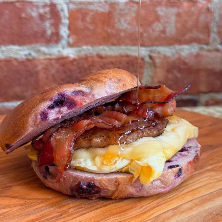 pouring maple syrup on a breakfast bagel at Broad Street Bagels in Kinderhook NY
