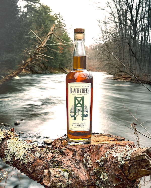 Black Creek Rye bottle on a rock in the middle of a stream by The Hudson House & Distillery in West Park NY