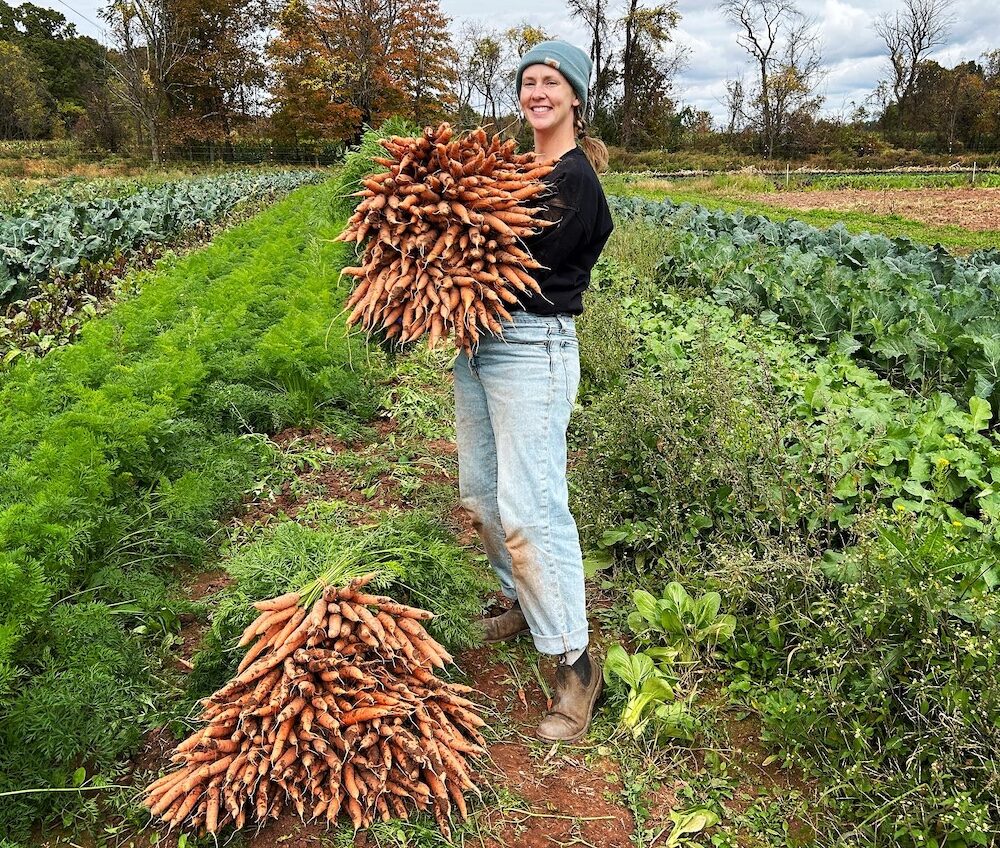 woman holding a bunch of carrots on the Lo Farm in Catskill NY