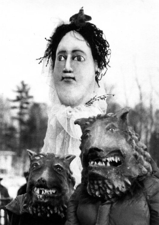 Protest march puppets in B&W of a woman and angry dogs by Amy Trompetter