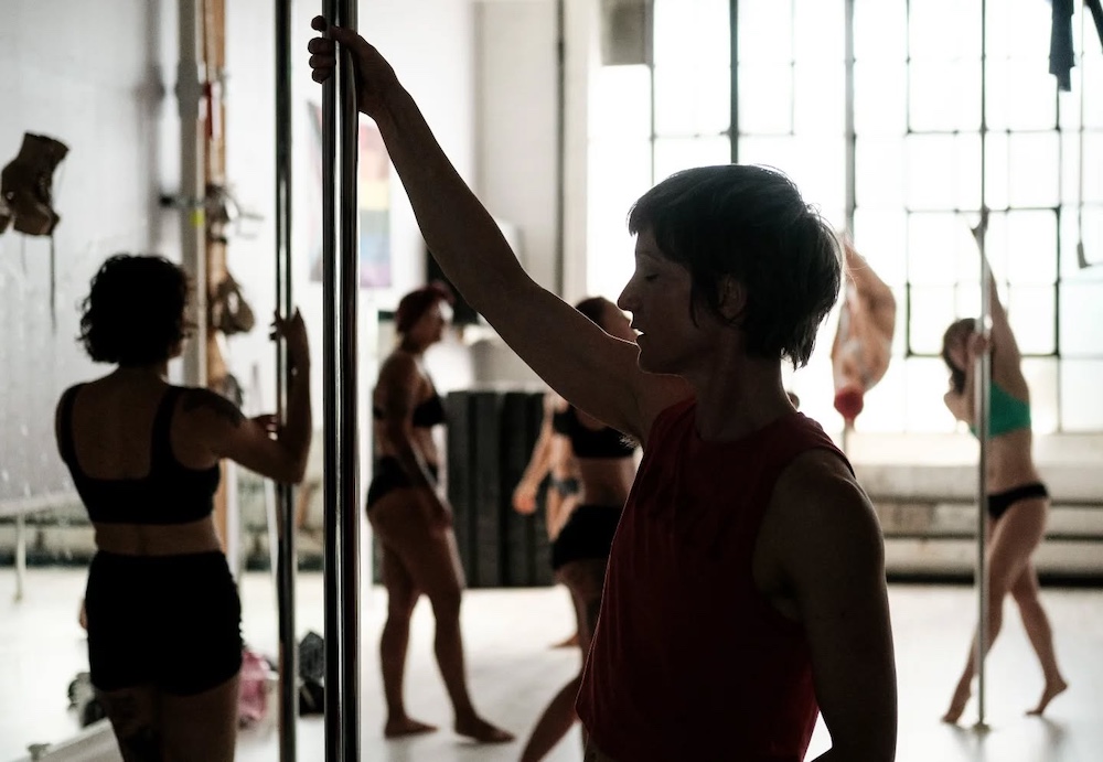 people in a dance studio practicing pole arts