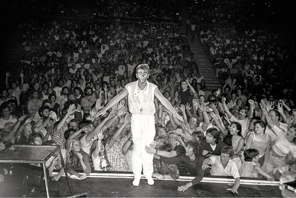 Peter Gabriel on the stage ready to trust fall into the crowd at Lay Hands On Me Tour