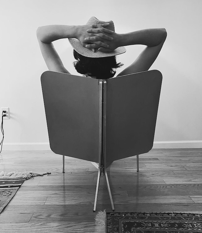 Woman sitting in modern aluminum chair -designed to curve her back-comfortable and modern