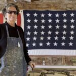 Artist Kate McGloughlin in her studio in front of a US heirloom flag.