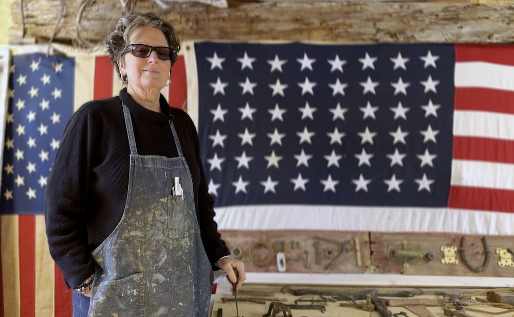 Artist Kate McGloughlin in her studio in front of a US heirloom flag.