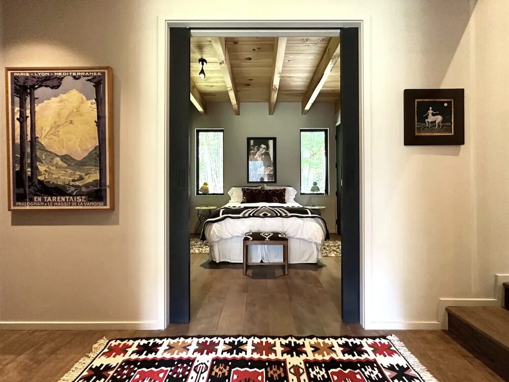 A shot of paintings on the wall next to the door opening with a view through to the bedroom's bed.