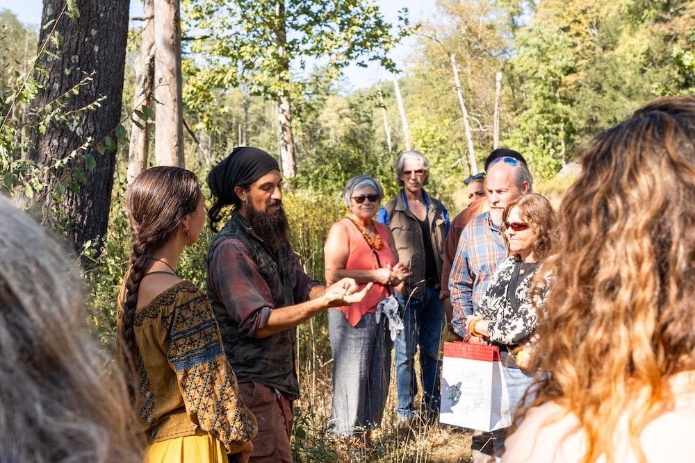 Dan showing a group of people out in the woods something in his hand that he foraged in the Hudson Valley NY with Sasha Botanica.