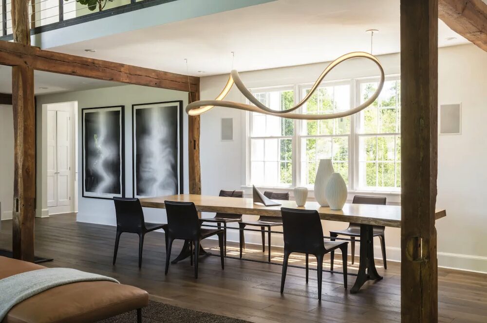 Dining room table with hanging light art and chairs.