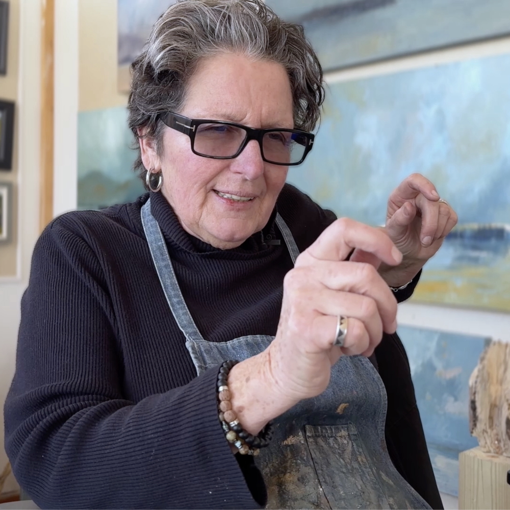 Artist Kate McGloughlin in her studio, talking with her hands.