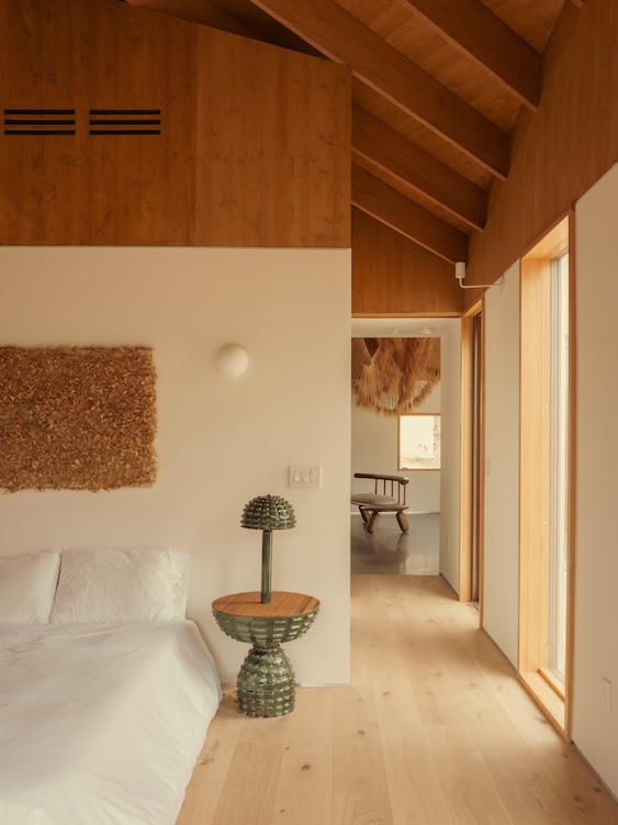 View of the master bed, side table with lamp and hallway at Ohayo Mountain House in Glenford NY.