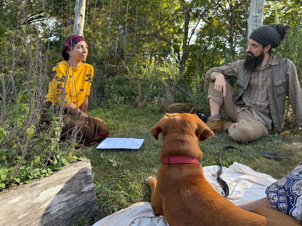 Sasha Botanica and Dan de Lion with their dog sitting and discussing their mentorship program in the woods.