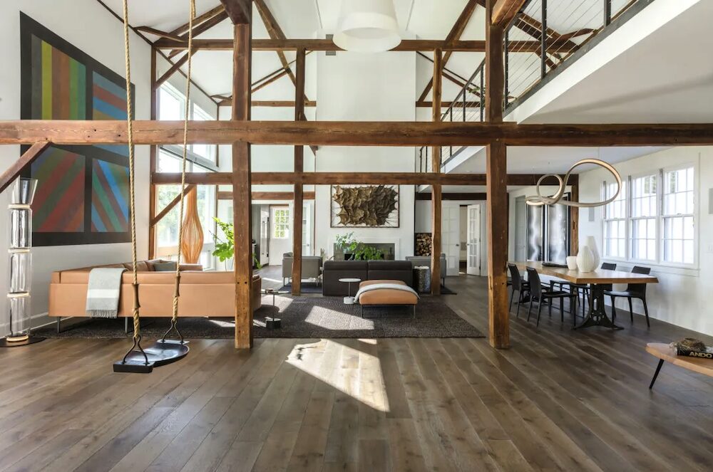 Open floor room with wooden posts, couches, dining room table and art.
