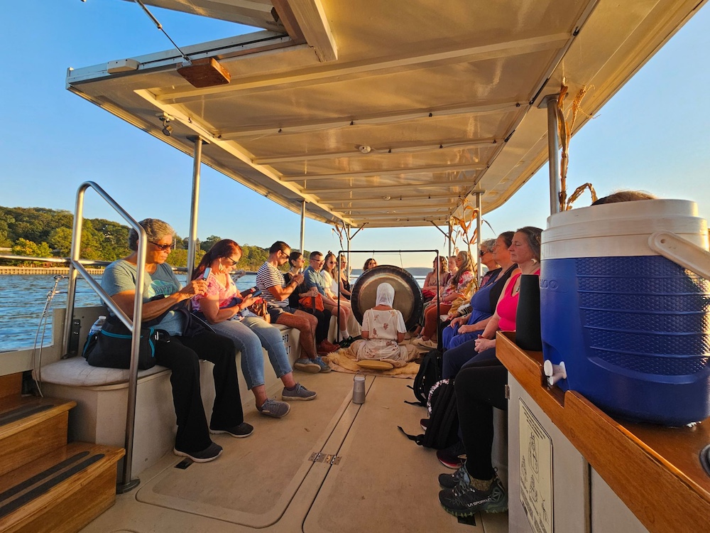 A group of people o the solar boat, Solaris, listening to a Gong bath experience on the Hudson River.