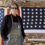 Artist Kate McGloughlin in her studio in front of a US heirloom flag.