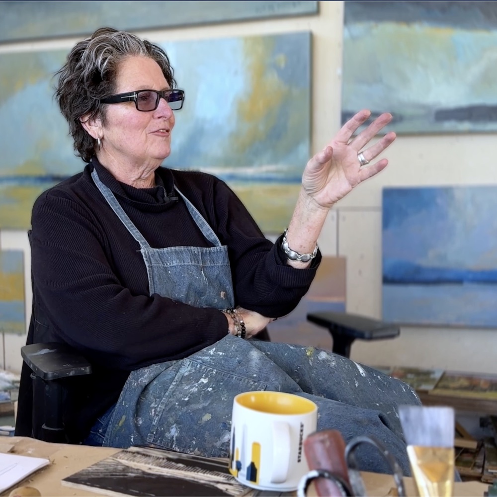 Artist Kate McGloughlin in her studio, talking with her hands.