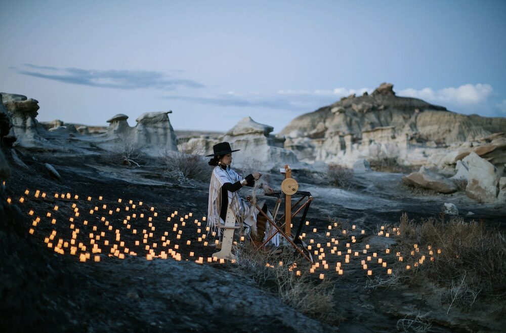 Woman in landscape weaving surrounded by candles - Peter Crosby